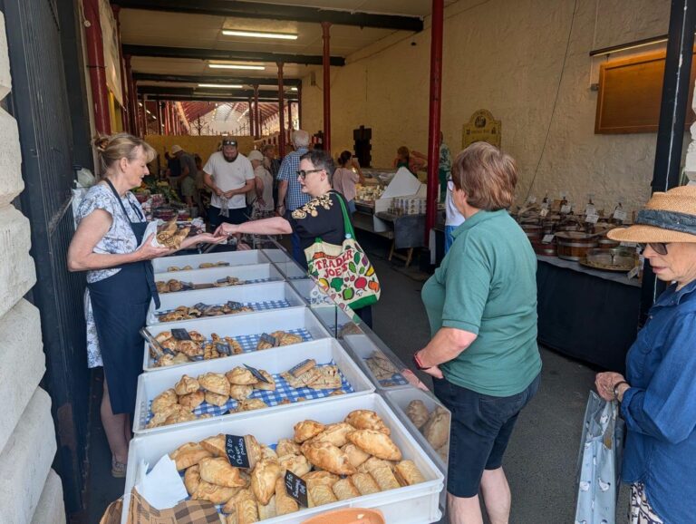 Customers buying baked goods at the front of the market