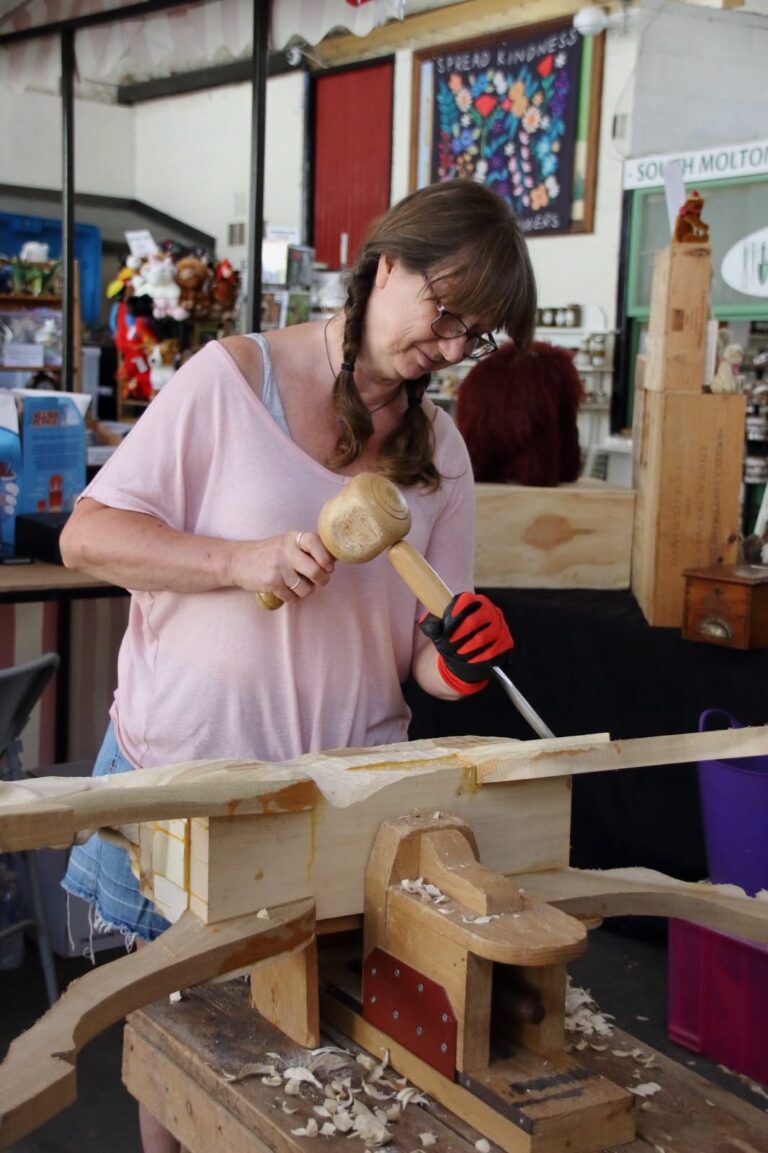 Debs using a mallet and chisel to carve a wooden rocking horse