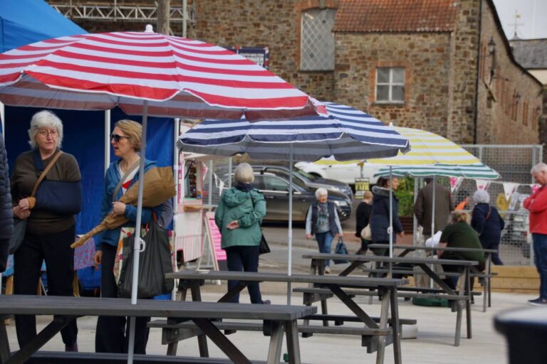 Visitors beside striped parasols and picnic tables in Drovers Yard