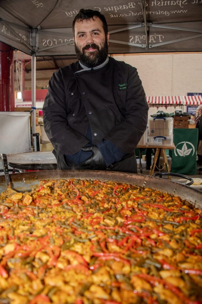 A food festival trader with a large pan of freshly cooked paella