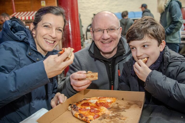 Visitors sharing pizza at the food festival
