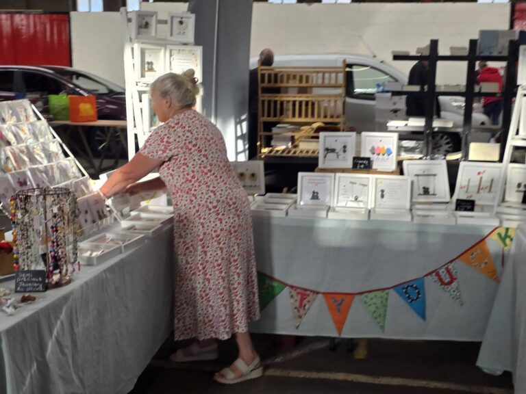 A trader arranging handmade gifts, jewellery and cards
