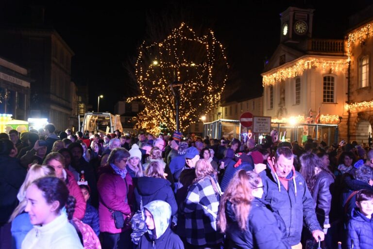A crowd beside the illuminated Christmas tree and Guildhall on Broad Street